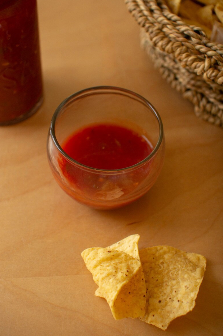 small bowl of red salsa with two chips beside it