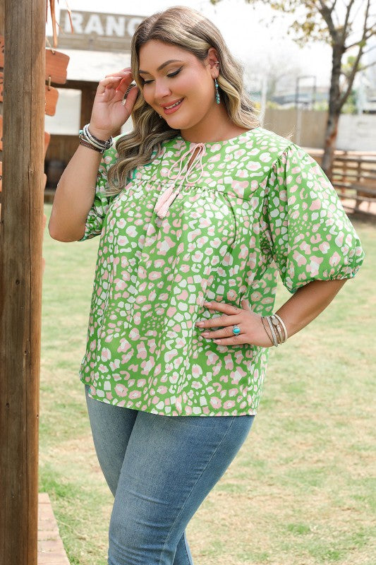 Woman wearing a green floral blouse and blue jeans outdoors.