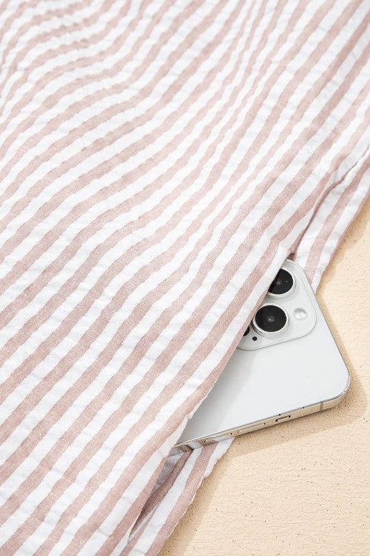 Silver phone with black camera lens on a pink and white striped fabric background