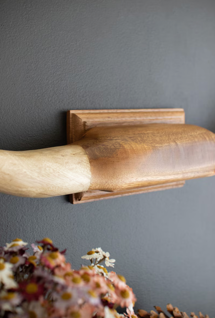 Wooden shelf against a gray wall with flowers in the foreground
