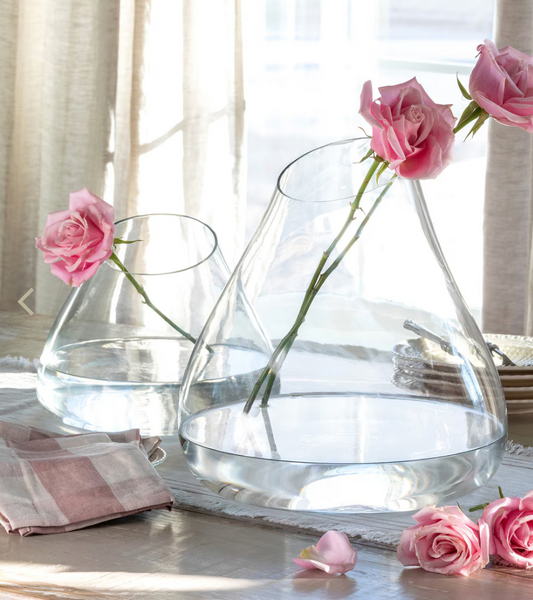 Clear glass vases with pink roses on a table with light background
