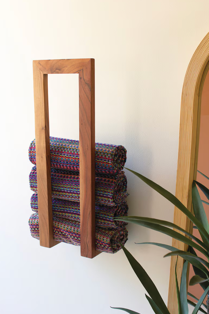 Wooden towel rack with folded towels against a white wall
