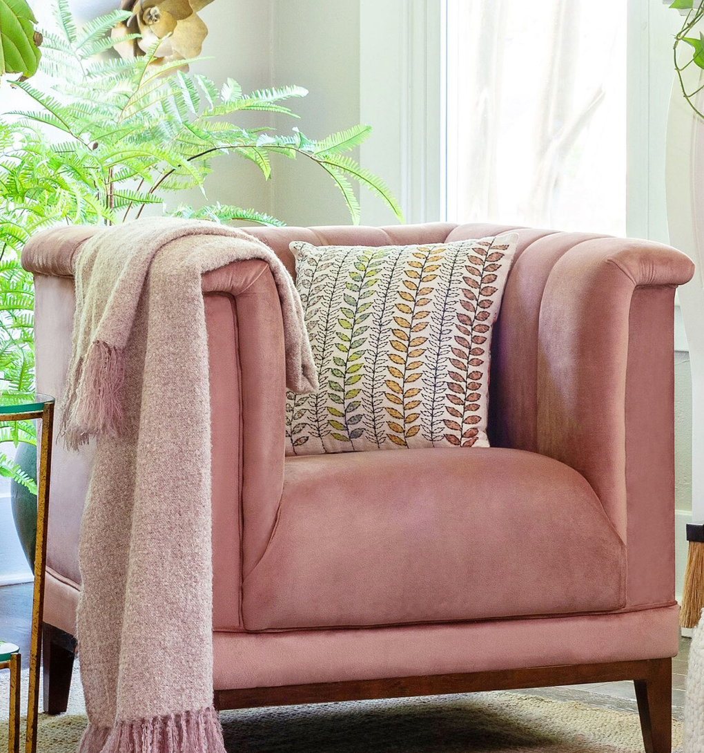 Pink armchair with a blanket and pillow in a bright room