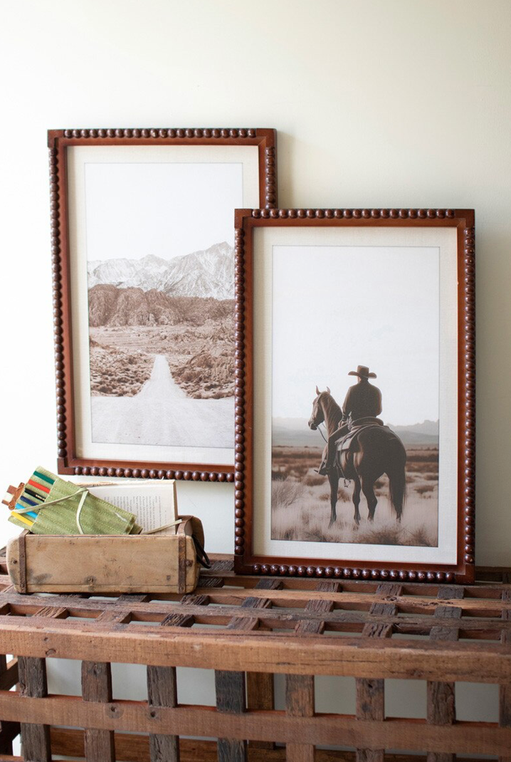 Two framed pictures on a wooden surface with a rustic background