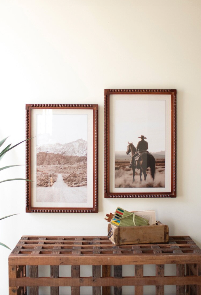 Two framed pictures on a wall above a wooden console table.