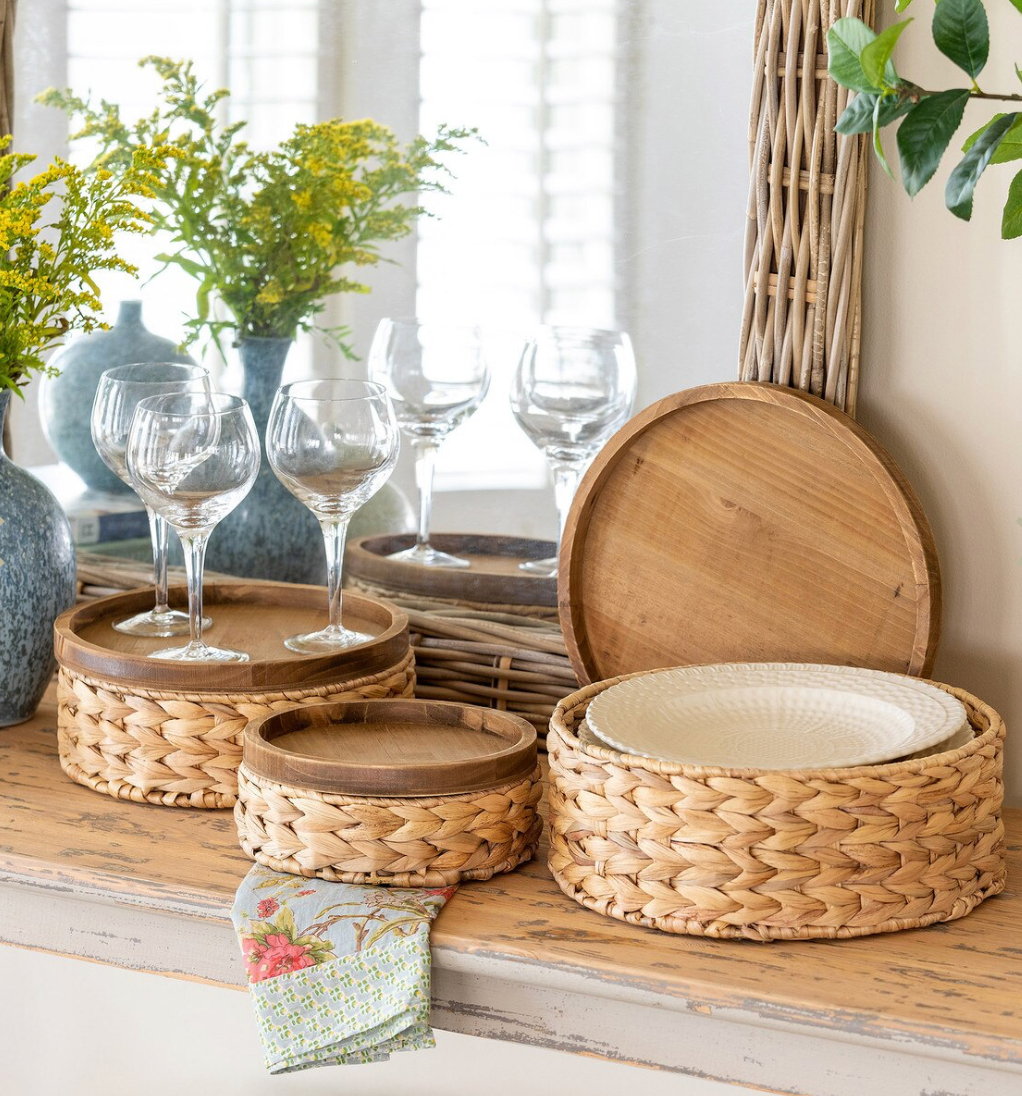 Wicker and wooden baskets on a table with glasses and plants in the background