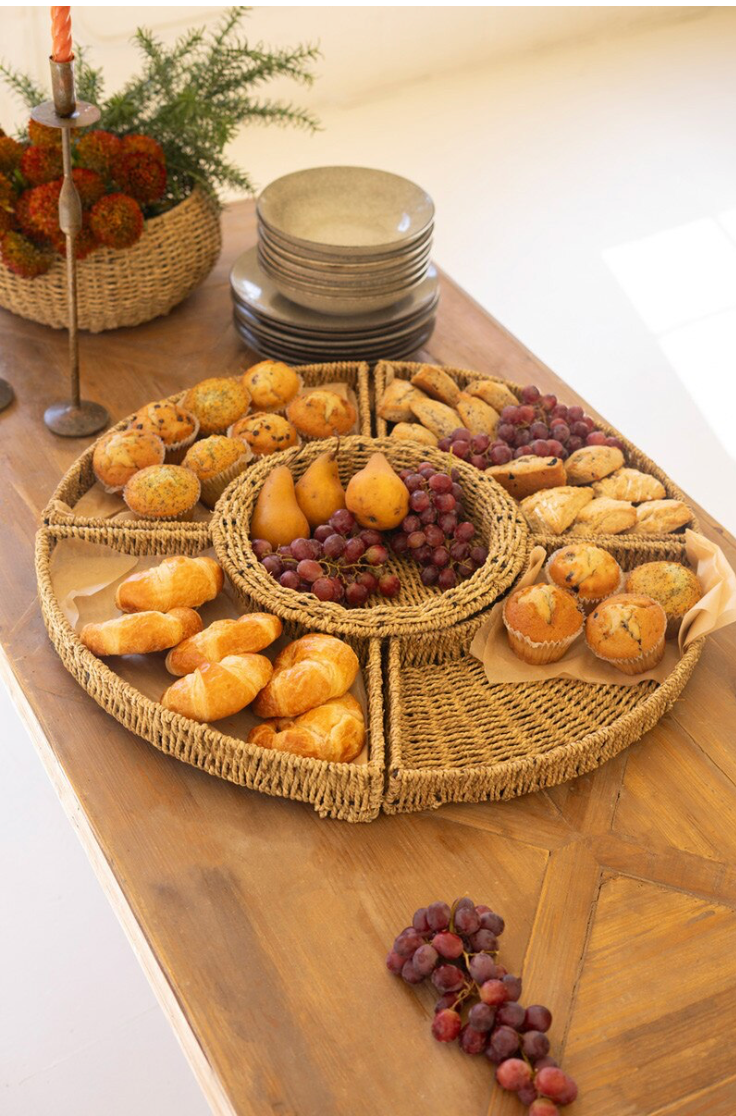 Wicker bread basket with bread and grapes on a wooden table