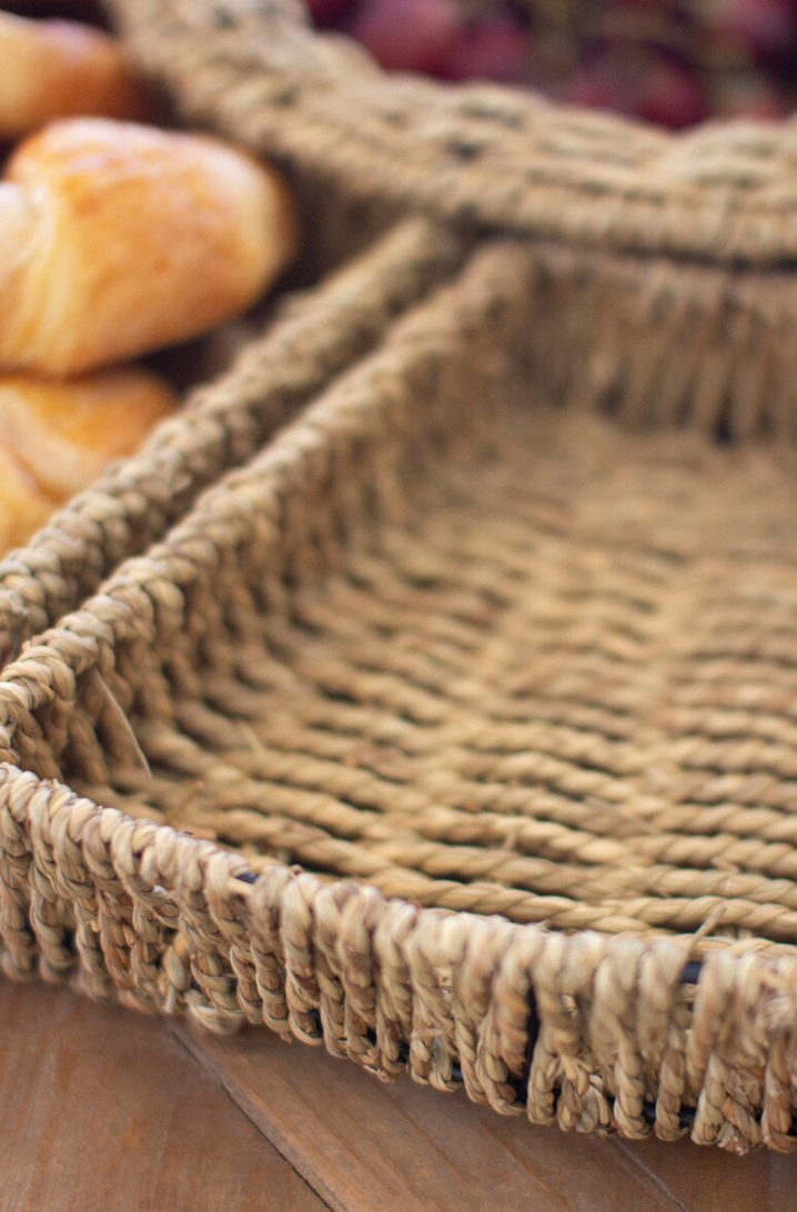 Close-up of a woven basket with bread and grapes on a wooden surface