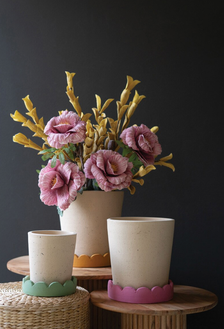 Decorative flower arrangement in a pot with two small ceramic cups on a dark background