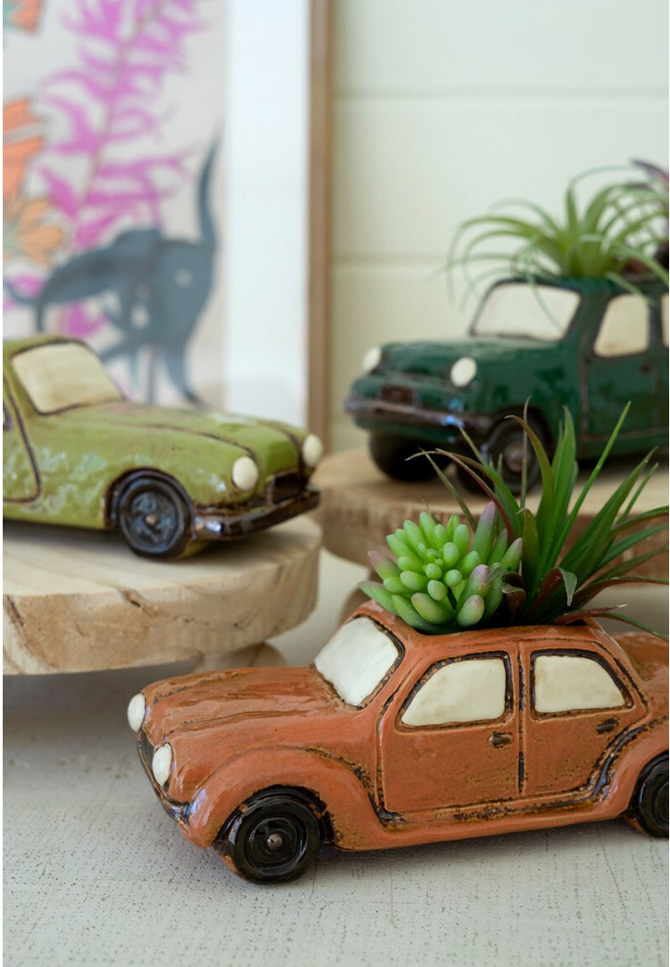 Decorative car models with plants on a neutral background