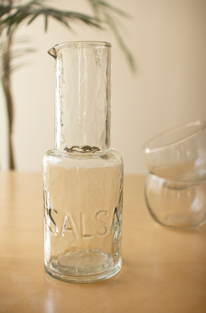 empty clear tall jar with salsa embossed on the bottom section with a white background