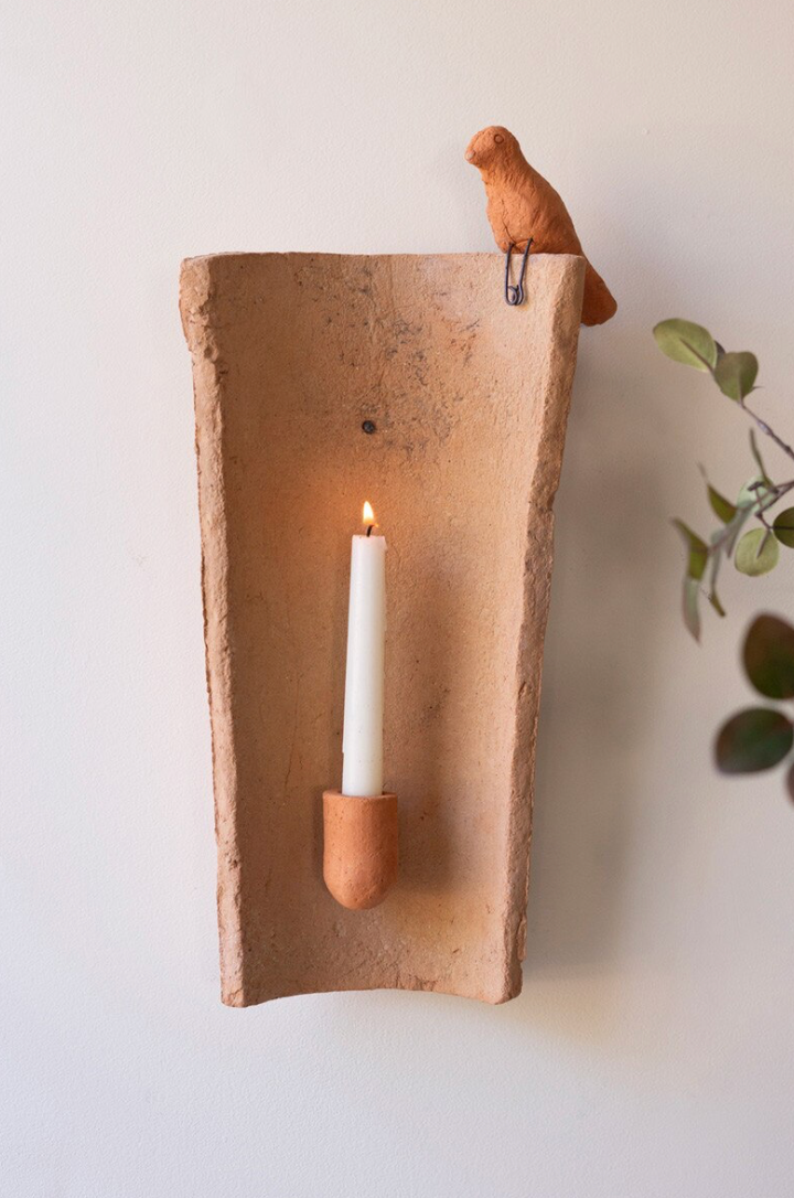 clay tile with taper holder and small clay bird perched on top right corner.