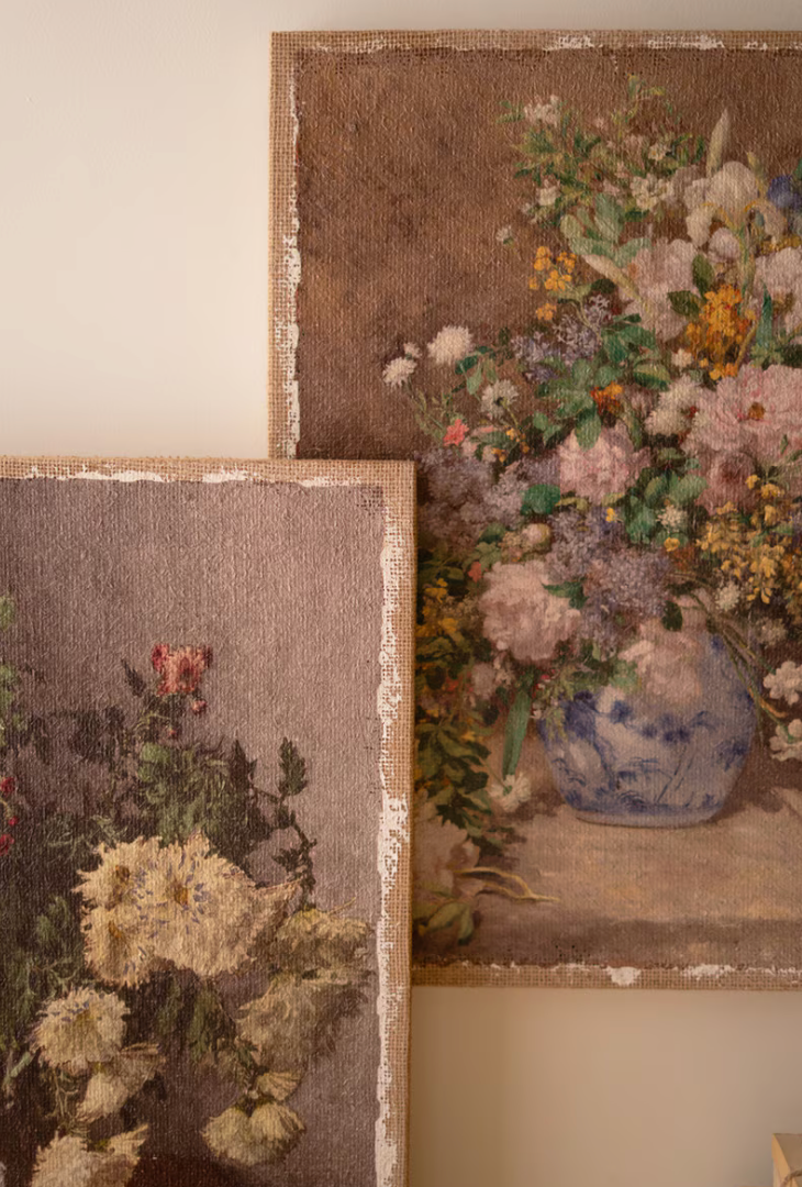 Two vintage-style floral tapestry wall hangings displayed on a beige wall. The larger tapestry on the right features a detailed bouquet of pink, purple, and yellow flowers in a blue-and-white patterned vase, while the smaller one on the left shows a different floral arrangement.