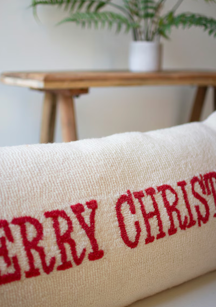 White pillow with red script reading Merry Christmas. 