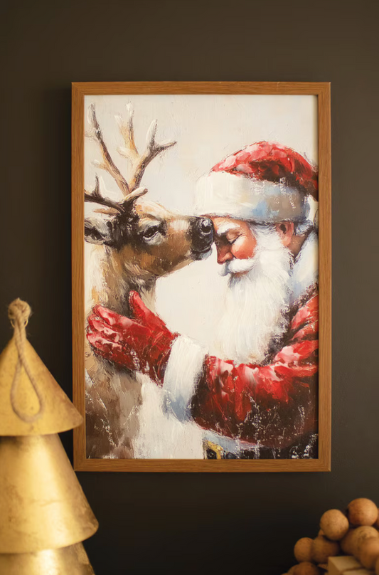  "Framed Santa with Deer Painting styled on dark wall above gold Christmas tree decorations and wooden accents, showing warm painterly scene of Santa and reindeer in oak frame in holiday vignette"
