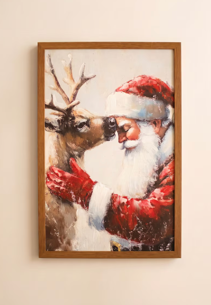"Framed Santa with Deer Painting displayed on cream wall showing full oak frame and painterly holiday scene of Santa in red embracing a reindeer with rich layered texture detail"
