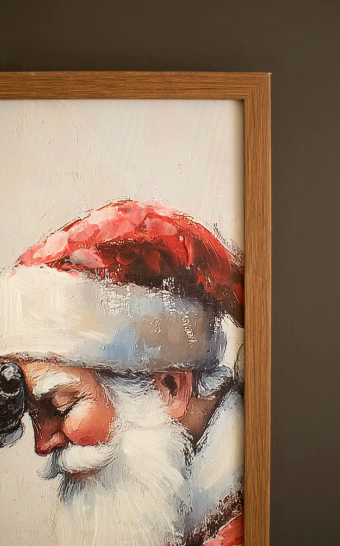 "Close-up detail of Framed Santa with Deer Painting showing layered paint-over-print texture on Santa's red hat and white beard with visible brushstroke depth and warm oak frame edge"