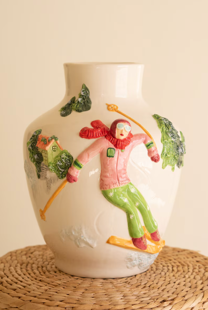 "Ceramic Christmas Vase with Skier full product shot on cream background showing wrap-around alpine ski scene with glossy white glaze finish"