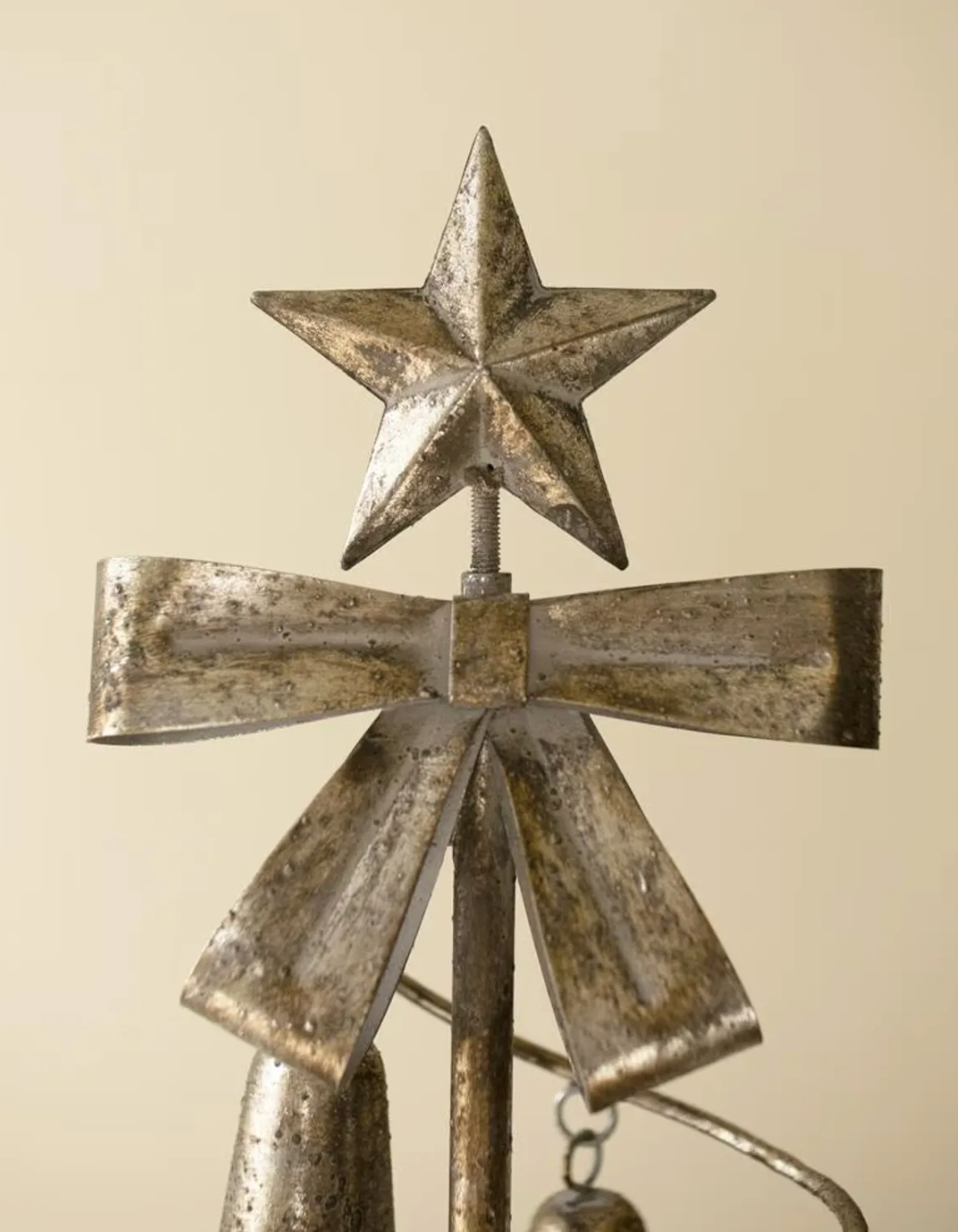 Close up of star on top of metal tree with a metal bow.
