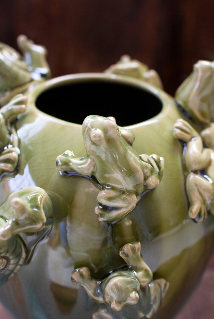 Green ceramic vase with fogs and snails close up shot
