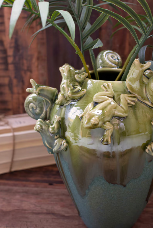 Green ceramic vase with fogs and snails and greenery inside
