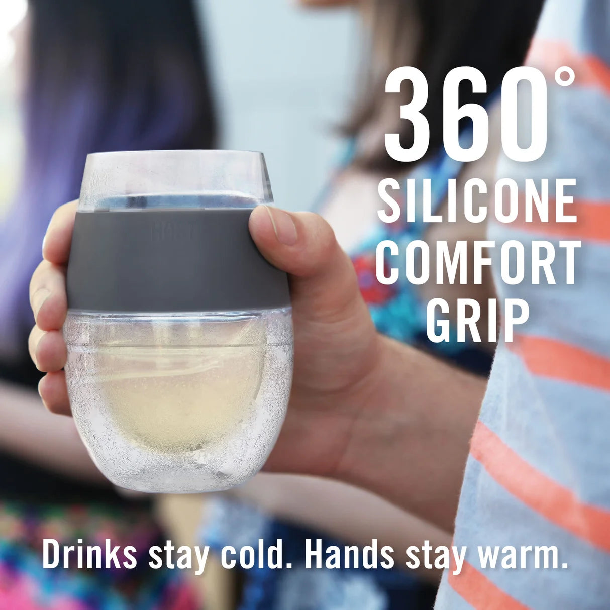 Hand holding a wine glass with a 360-degree silicone comfort grip, surrounded by people.