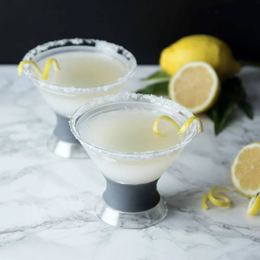 Two lemon-themed cocktails with lemon twists on a marble surface.