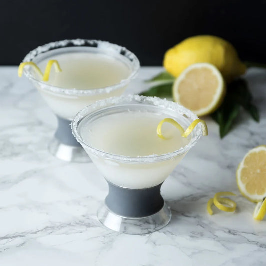 Two lemon-themed cocktails with lemon twists on a marble surface.